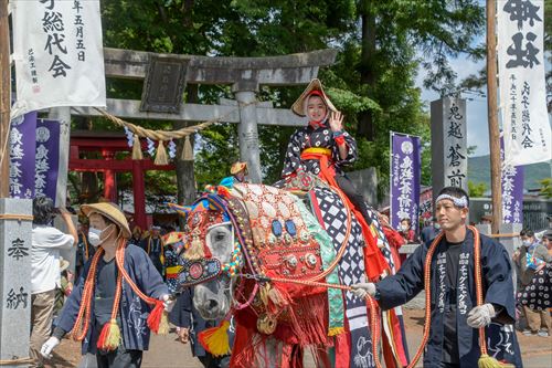 鳥居の前で子供が馬にまたがっている様子