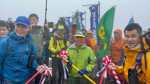 登山者が旗の前で並んでいる様子