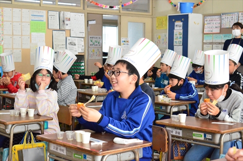 子どもたちが机に座り食べ物を食べている様子