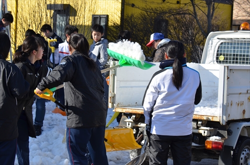 人々が雪をトラックの荷台に載せる様子