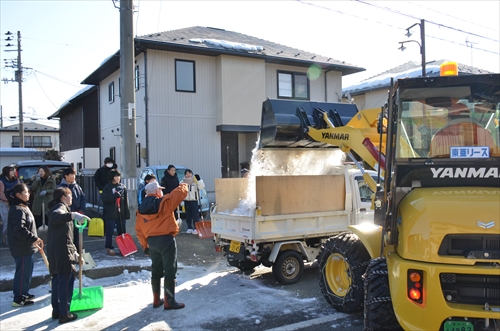 作業車がトラックの荷台に雪を載せている様子