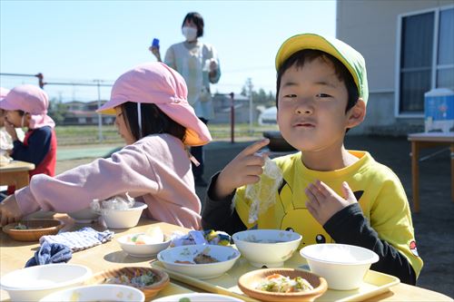 屋外で子どもたちが食事をしている様子