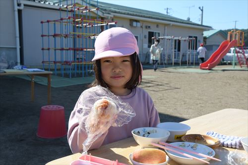 屋外で子どもたちが食事をしている様子