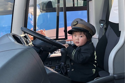 たきざわバスまつりで行われた、制服を身に着けバスの運転席で記念写真を撮る様子