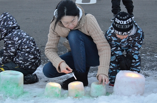 親子で雪灯篭に火を灯す様子