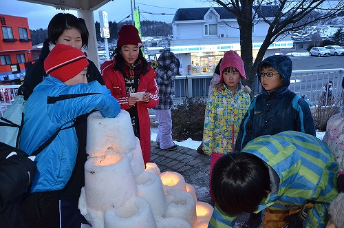 雪灯篭に火をつける子ども