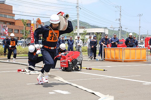 ホースを担ぎ運ぶ隊員の写真