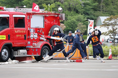 消防競技会、ポンプ車にホースをつなぐ隊員の写真