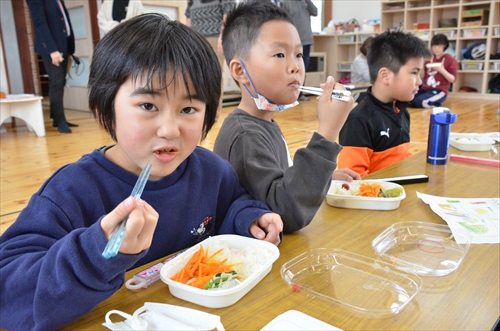 お弁当を頬張る男子児童