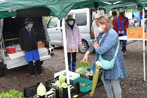 女性が売られている野菜を指さしている様子