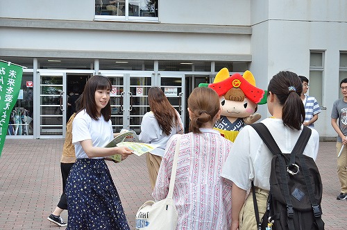 学生が屋外でチラシ配りを行っている様子