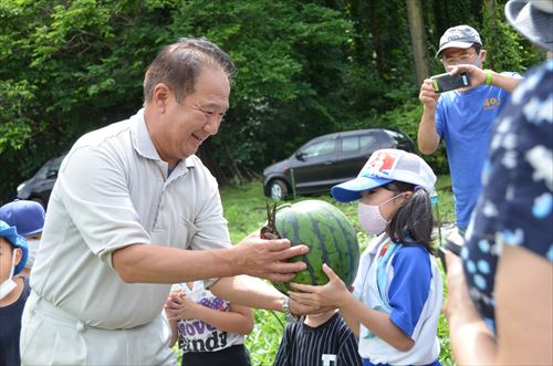 子どもが井上幸彦さんにスイカを渡している様子