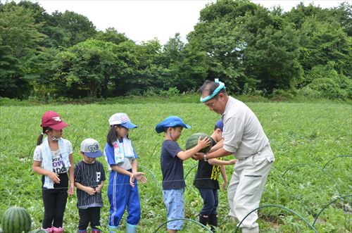 子どもたちが井上幸彦さんにスイカを渡している様子