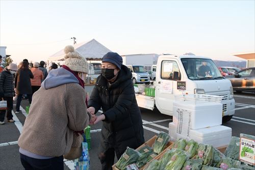 女性が店舗で野菜を購入している様子