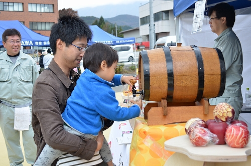 子どもが樽から飲み物を汲んでいる様子