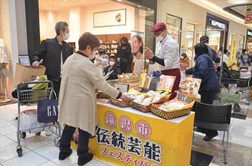 人々が売店で商品を眺めている様子