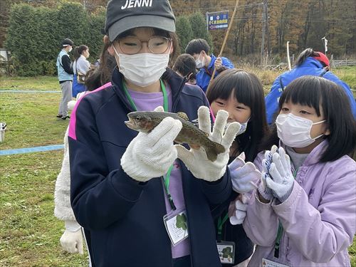 魚を手に持ち眺めている子どもたちの写真