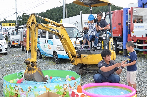 ショベルカーに一緒に乗ってボール掬いをする子供たち