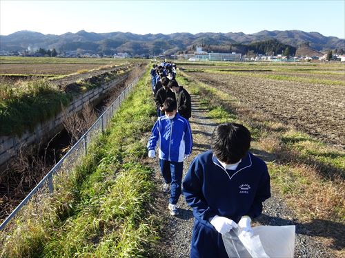 農道のゴミを並んで拾う学生達の様子