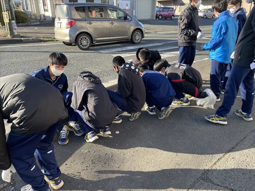 道路端のゴミを拾う学生達の様子