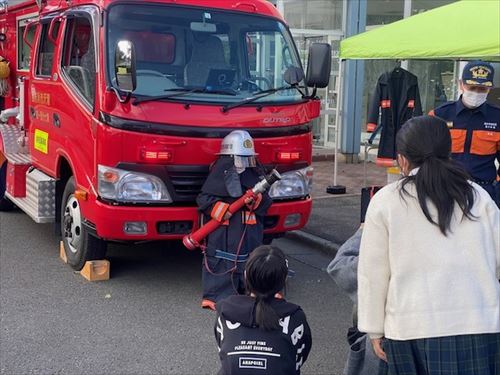 子どもが防火衣を着て消防車の前で記念撮影