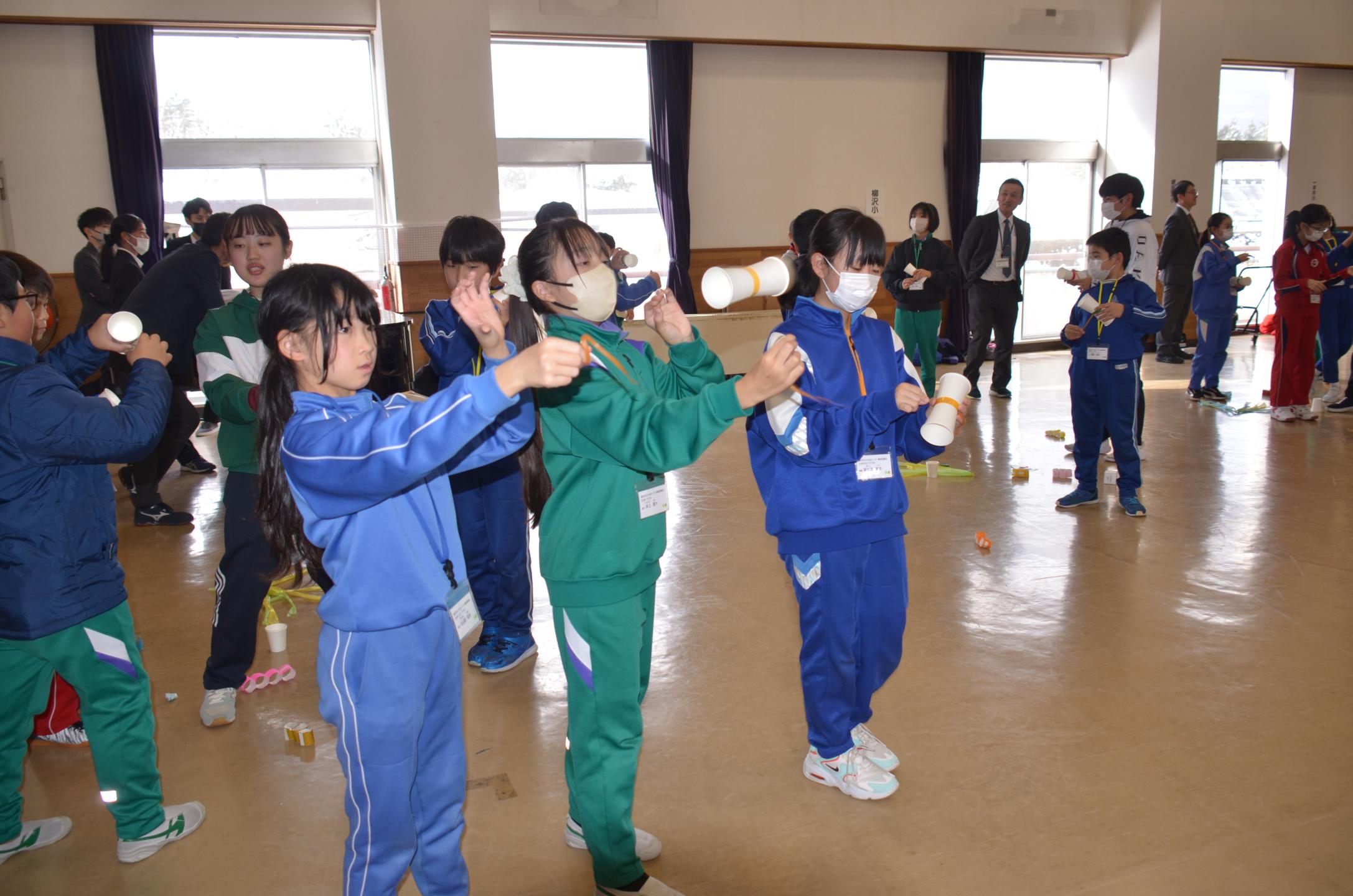 紙コップで作成したおもちゃで遊ぶ児童たち